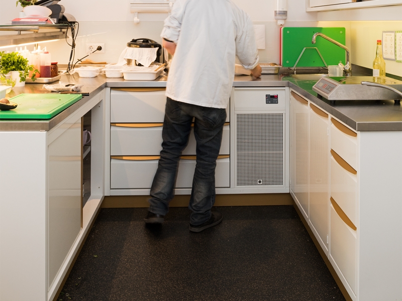 "Miss Maki"-Mitarbeiter bei der Speisenzubereitung in der Showküche. CNS-Unterbauten und Wandhängeschrank in den CI-Farben weiß und gold ausgeführt (inkl. Sockel)