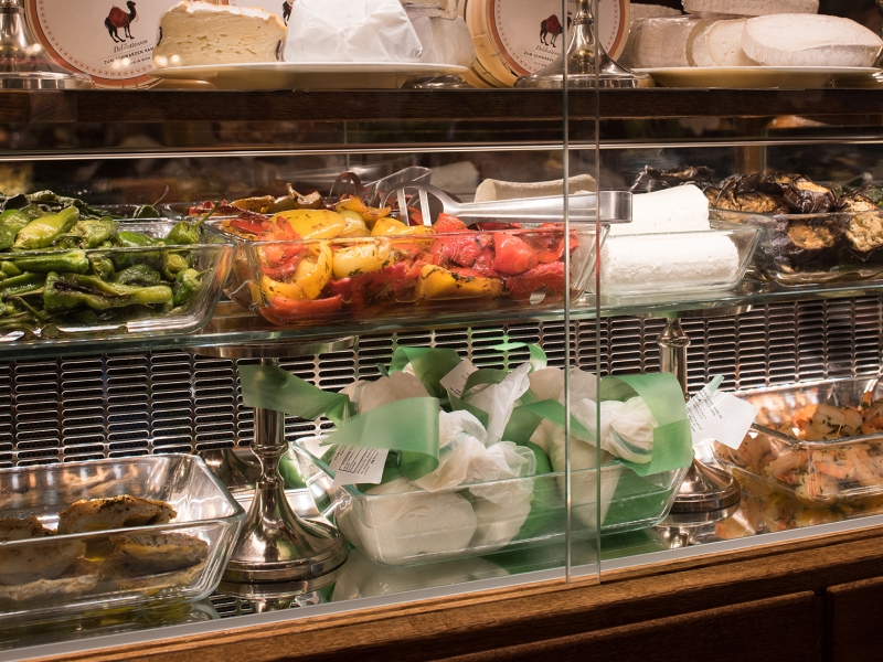Detail-Aufnahme der Sonderkühlvitrine mit Präsentationsfläche mit Spiegelblech aus Edelstahl (Speisenpräsentation); im Hintergrund perforierte Blende für optimale Luftführung