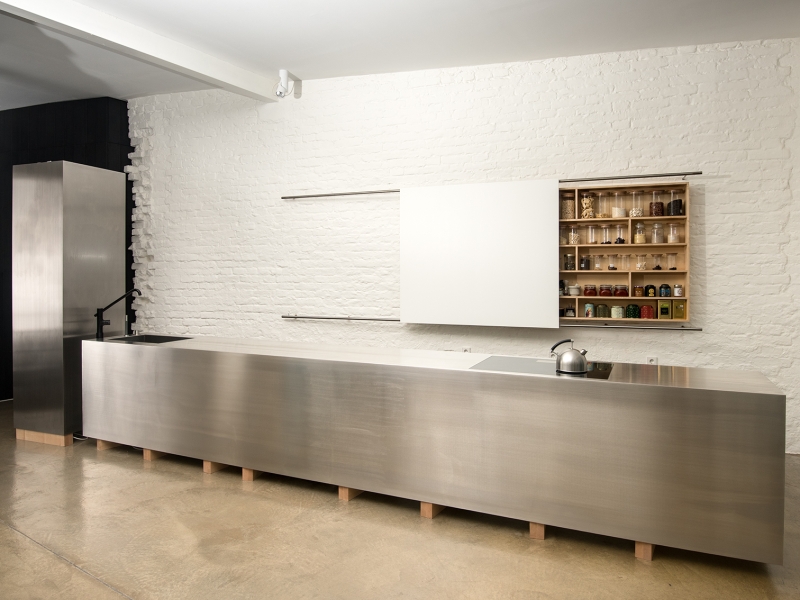 Design-Kochblock aus Edelstahl, 5mm-Blech, scharfkantig und fugenlos dicht verschweißt nach Wunsch des Architekten; Kühlschrank in daneben stehendem Edelstahl-Monolithen integriert