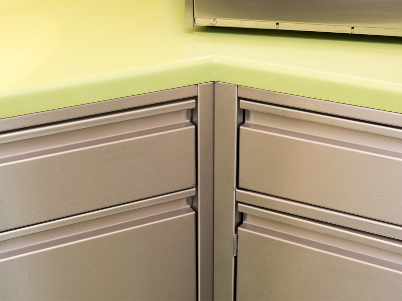 Detail-Aufnahme von Labor-Verbau mit grüner Corian-Platte sowie Edelstahl-Unterbauten mit Laden mit gekanteter Griffleiste