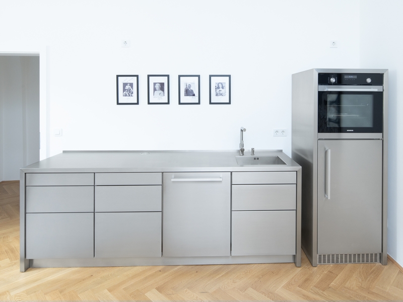 Gesamtaufnahme von Designküche in Edelstahl; Besonderheit = die Seitenhäupter sind fugenlos in einem Stück mit der Arbeitsfläche gefertigt