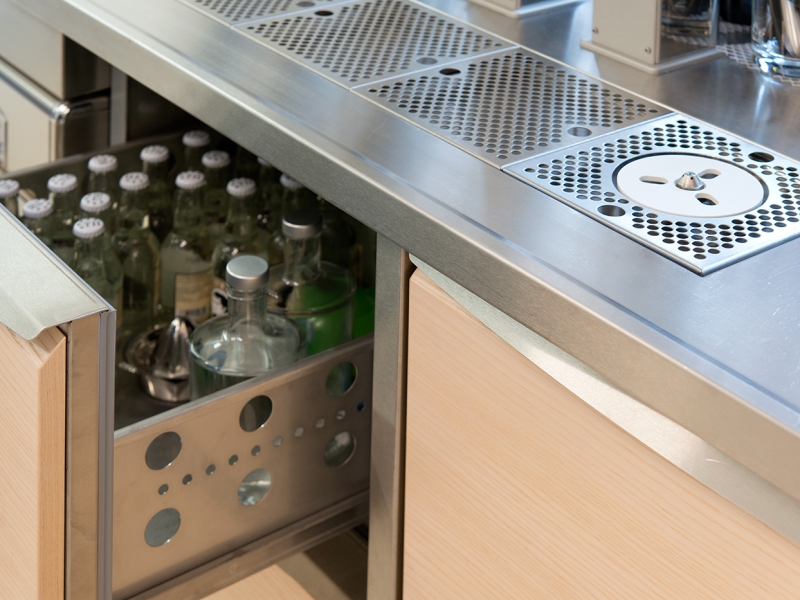 Fugenlos eingeschweißte Tropftasse mit Gläserdusche mit Arbeitsplatte mit gekantetem Wulstrand (Edelstahl); Unterbau = Sonder-Thekenkühlung mit integrierten Holzfronten nach Kundenwunsch